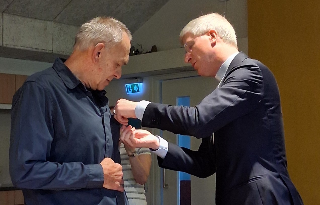 Obe van der Meer ontvangt de waarderingsspeld van de Heilige Titus Brandsmaparochie uit handen van pastoor Arjen Bultsma